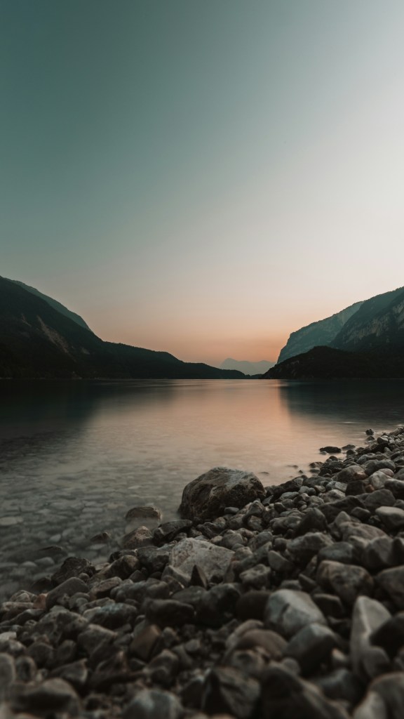 湖畔山峦日落石滩静谧景色照片