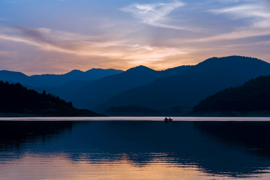 湖畔山影夕阳小舟照片